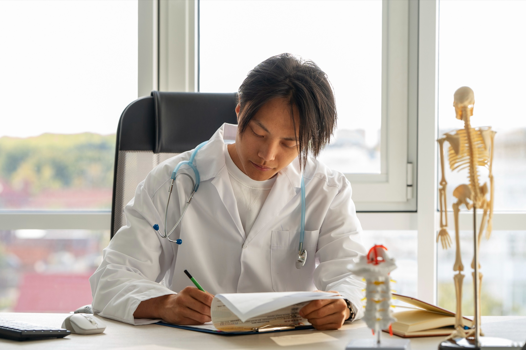 Focused medical student studying with books and laptop